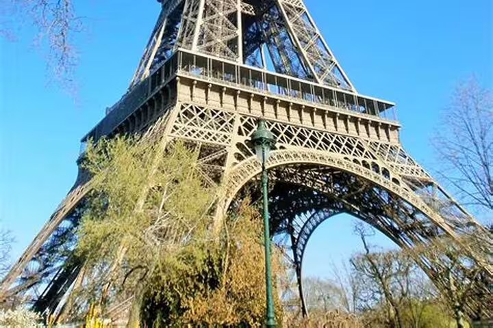 Close-up view of the Eiffel Tower base with green lamp post and trees, Paris