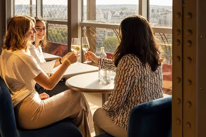Guests toast with champagne at Eiffel Tower lunch, enjoying panoramic Paris views on private tour