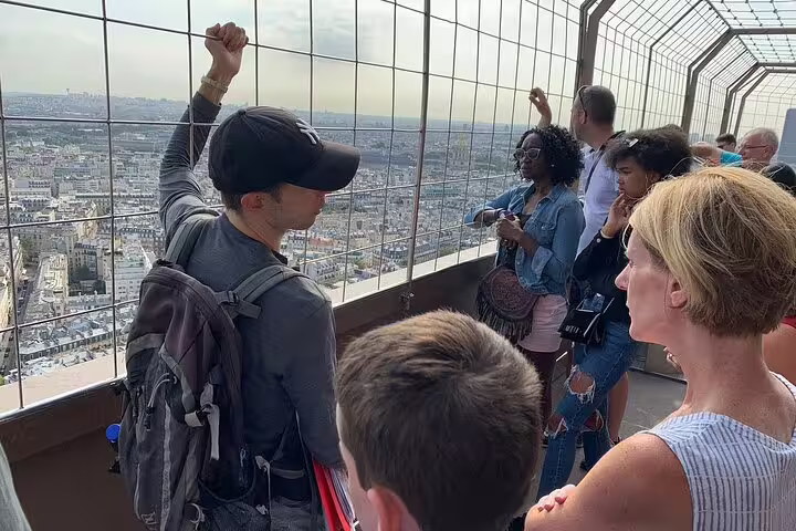 Tourists enjoying panoramic views of Paris from Eiffel Tower observation deck on guided climbing tour