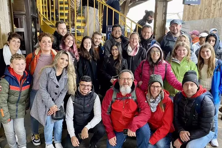 Large tour group posing together at the Eiffel Tower in Paris on a guided sightseeing tour