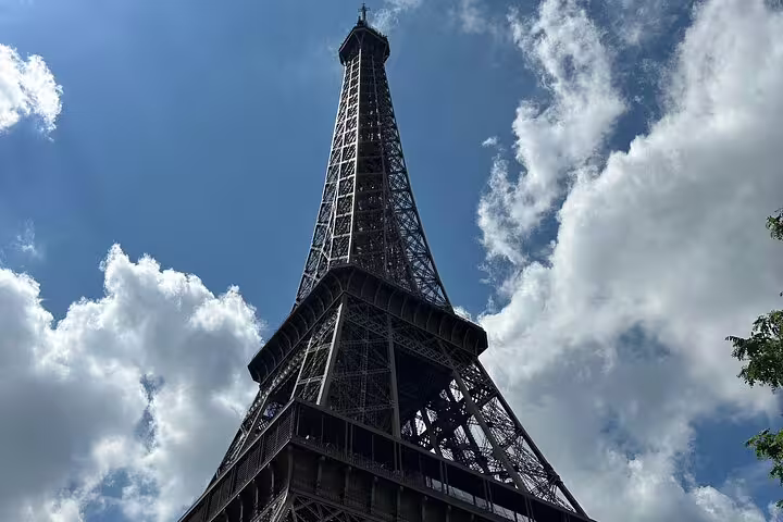 Eiffel Tower seen from below against a blue sky with clouds, Paris