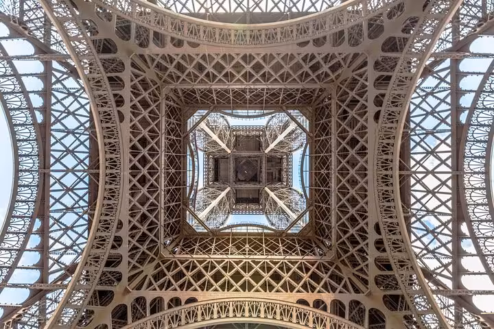 Looking up inside the Eiffel Tower iron lattice on a private tour with luxury lunch and Seine cruise