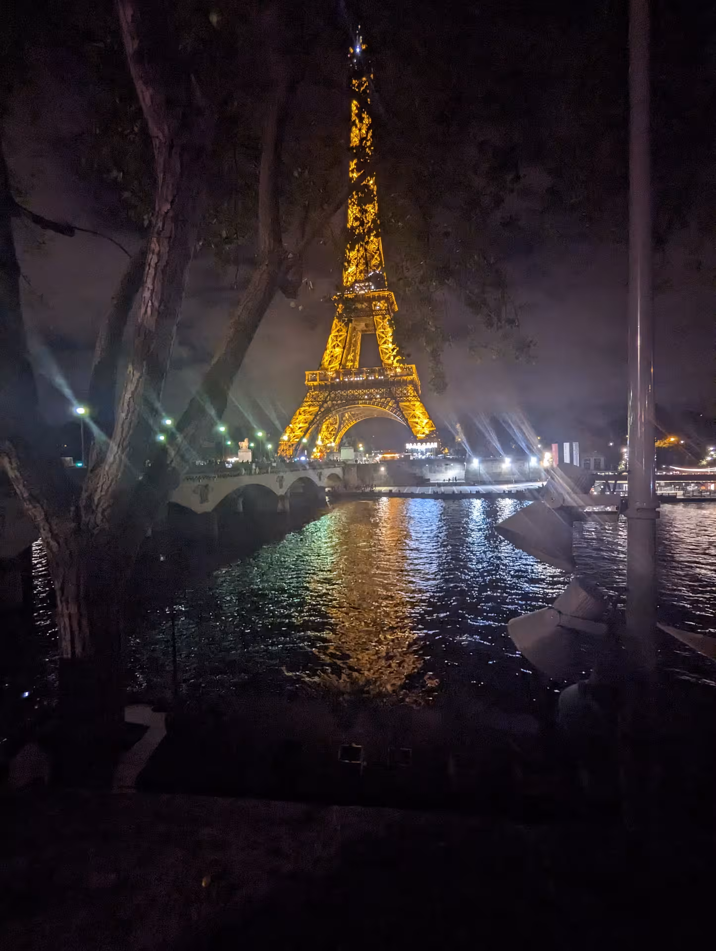 Eiffel Tower illuminated in golden light at night reflected on the Seine River, Paris