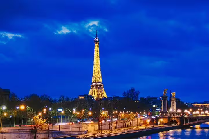 Eiffel Tower illuminated at night with golden lights reflected on the Seine River in Paris