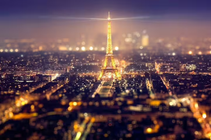 Eiffel Tower illuminated at night with golden lights over Paris cityscape aerial view