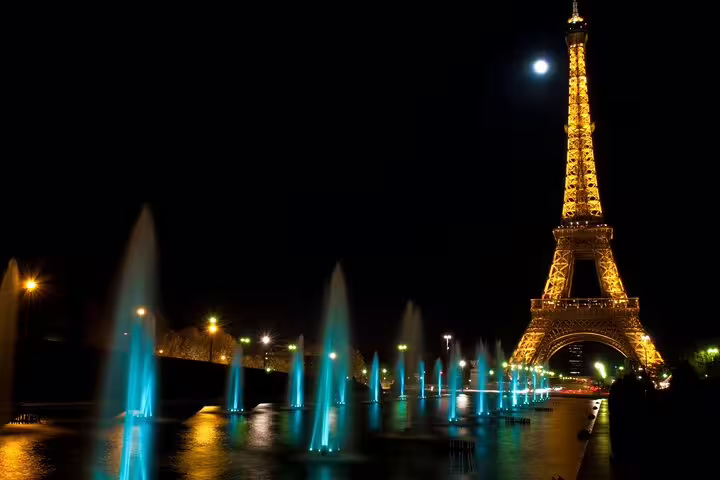 Eiffel Tower illuminated at night with glowing blue fountains at Trocadéro, Paris