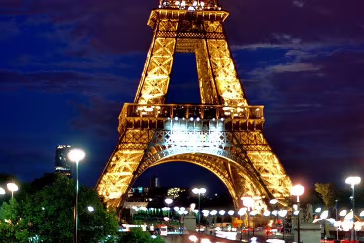 Eiffel Tower illuminated at night with golden lights against a deep blue sky in Paris