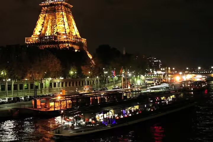 Illuminated Eiffel Tower at night with a Seine River dinner cruise boat in Paris