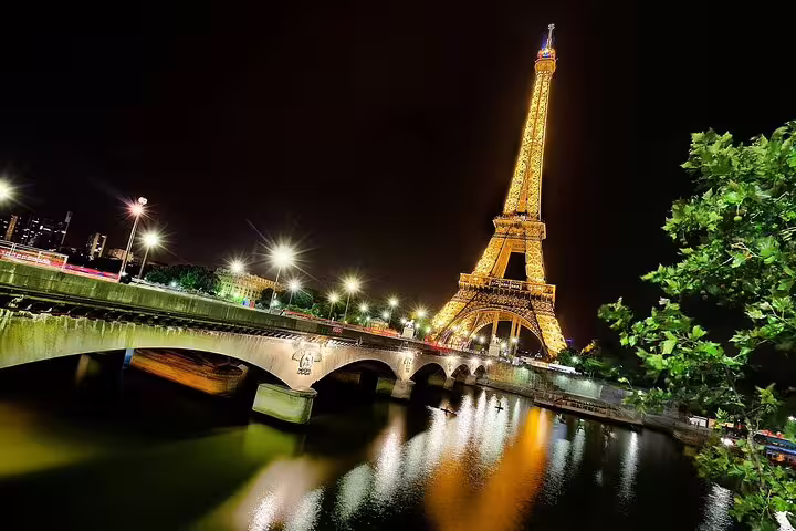 Eiffel Tower illuminated at night with Seine River and bridge in Paris