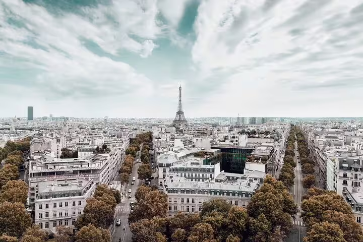 Aerial view of Paris with Eiffel Tower rising above Haussmann boulevards and tree-lined avenues