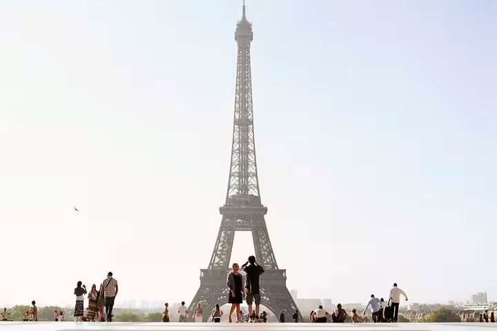 Tourists gathered at Trocadero plaza with iconic Eiffel Tower rising against a bright Paris sky
