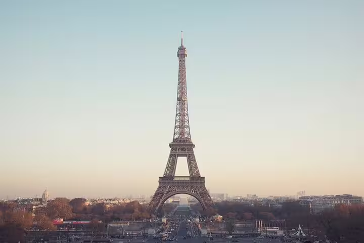 Eiffel Tower standing tall at sunset with Paris cityscape in the background