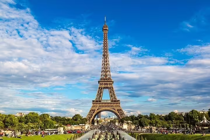 Eiffel Tower standing tall over green Champ de Mars park in Paris on a sunny day