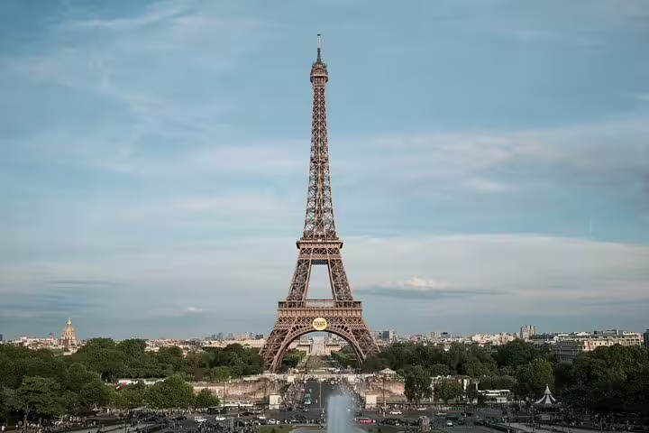 Eiffel Tower standing tall over Paris cityscape with fountains and tree-lined avenue in foreground