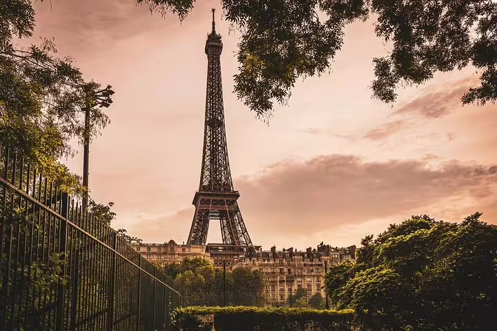 Eiffel Tower framed by lush trees at golden sunset in Paris