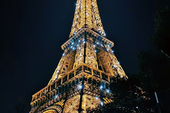 Eiffel Tower illuminated at night with golden lights against dark sky, Paris