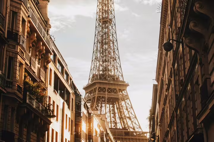 Eiffel Tower viewed from a Parisian street at golden hour with Haussmann buildings