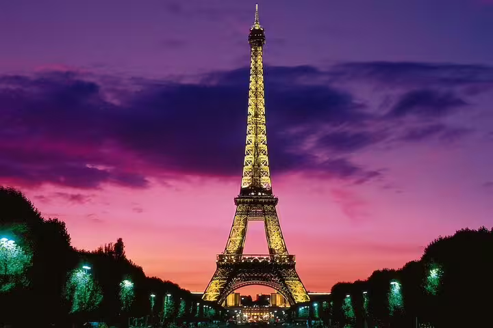 Eiffel Tower illuminated at sunset with vibrant purple and pink sky in Paris, France