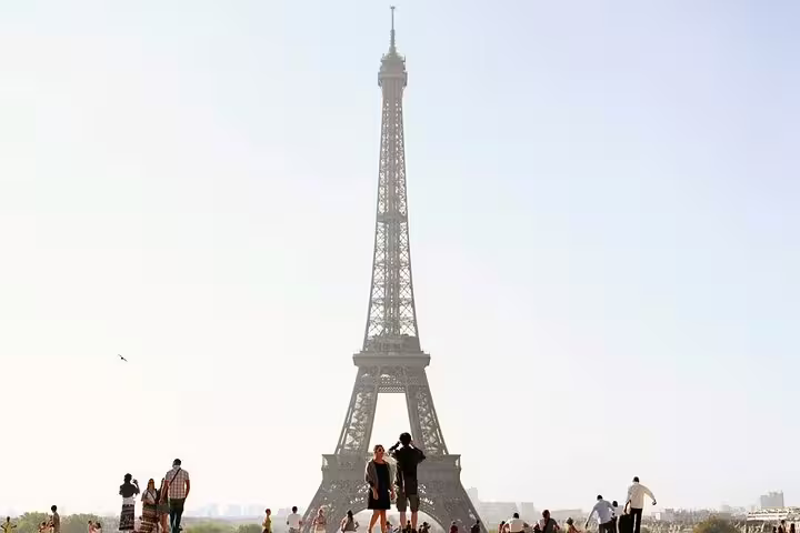 Tourists gathered at Trocadéro plaza with iconic Eiffel Tower rising against a bright Parisian sky