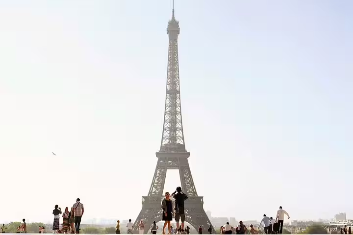 Tourists gathered at Trocadero plaza with iconic Eiffel Tower standing tall in Paris on a hazy day
