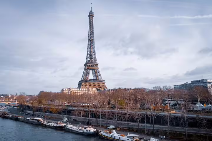 Eiffel Tower viewed from the Seine River with boats docked along the riverbank in Paris