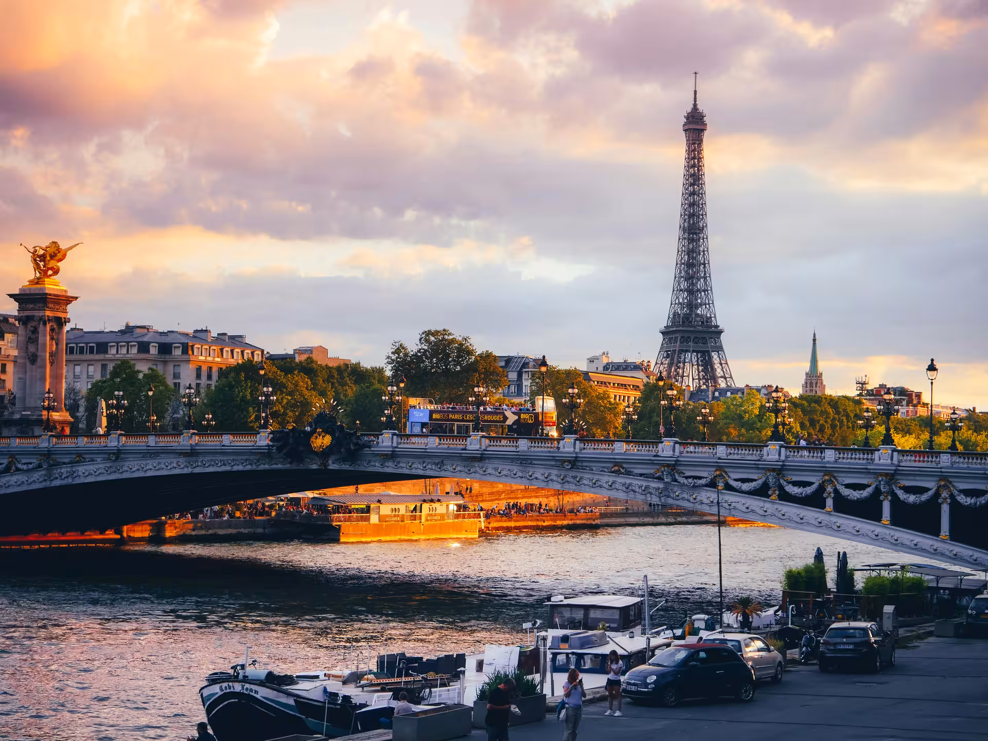 Eiffel Tower rising above the Seine River and Pont Alexandre III bridge at golden sunset in Paris