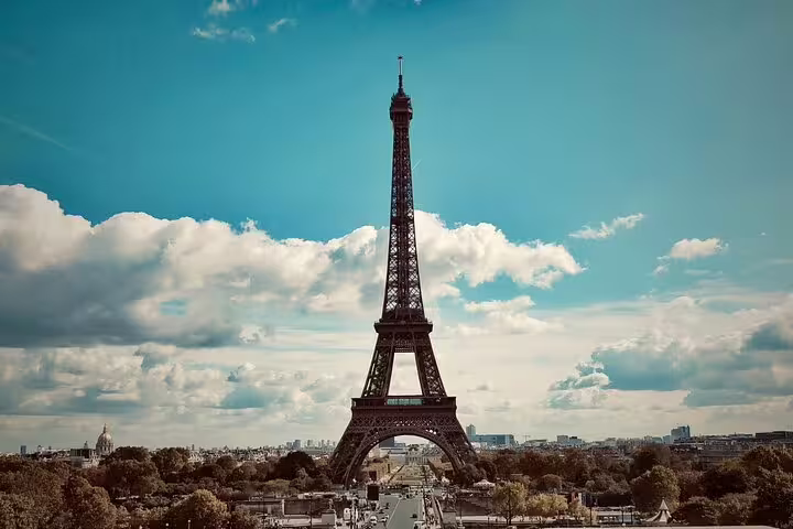 Eiffel Tower rising above Paris skyline with blue sky and clouds