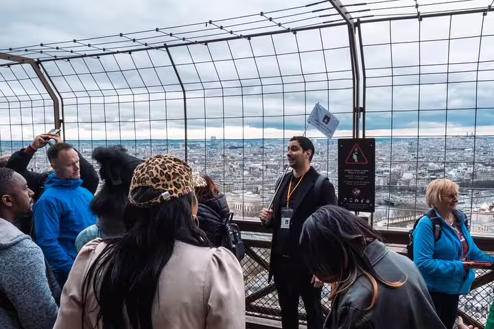 Tour guide leading a group of tourists on the Eiffel Tower top floor observation deck overlooking Paris