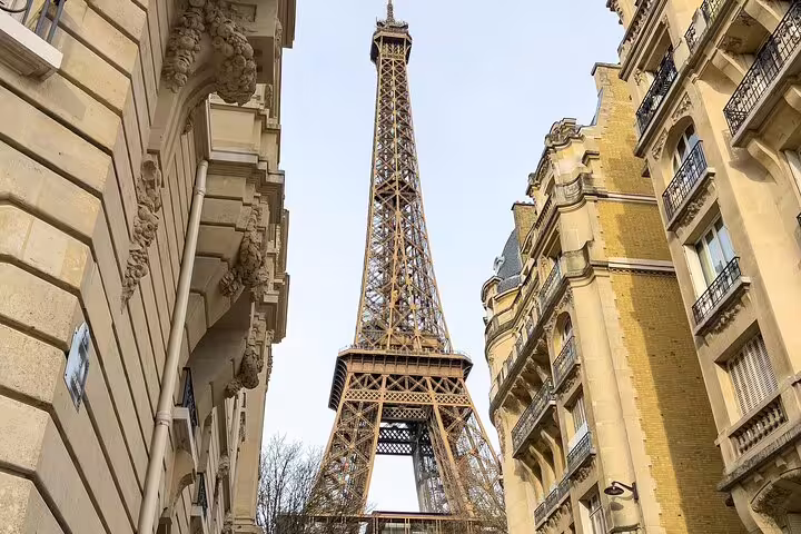 Eiffel Tower viewed from a narrow Parisian street flanked by classic Haussmann buildings
