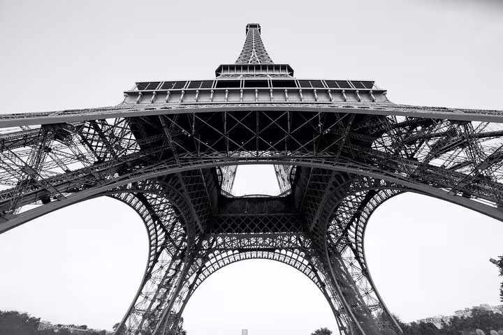 Looking up at the Eiffel Tower iron lattice structure from below in black and white
