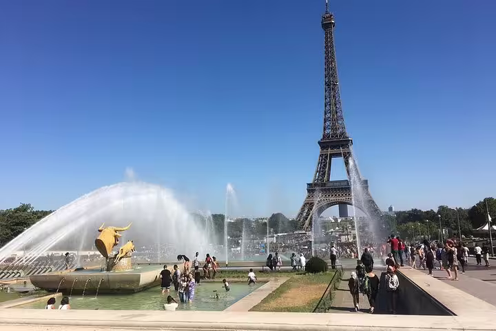 Eiffel Tower view from Trocadero fountains with golden bull sculptures and crowds in Paris