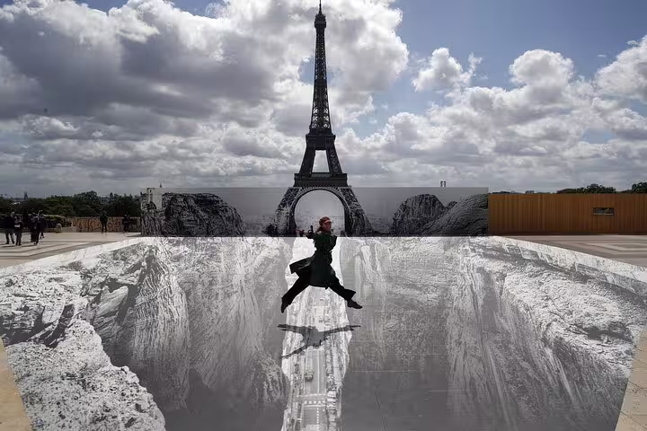 Person jumping over large trompe l'oeil artwork on Trocadero plaza with Eiffel Tower in background, Paris