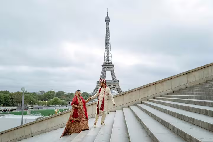 Indian couple in traditional wedding attire holding hands on Trocadero steps with Eiffel Tower backdrop