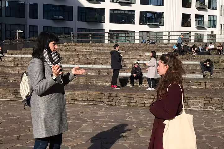 Local guide talking with visitor on Eindhoven future-focused city tour near modern architecture and steps