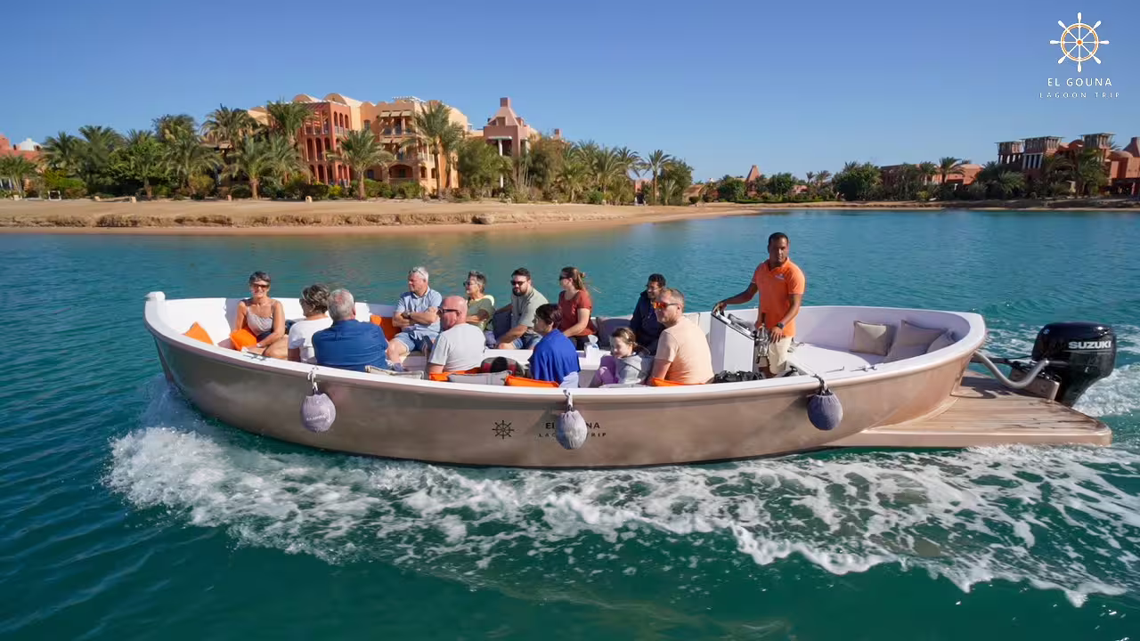 Sightseeing boat carrying tourists across El Gouna lagoon, Red Sea, with palm-lined resorts on city tour