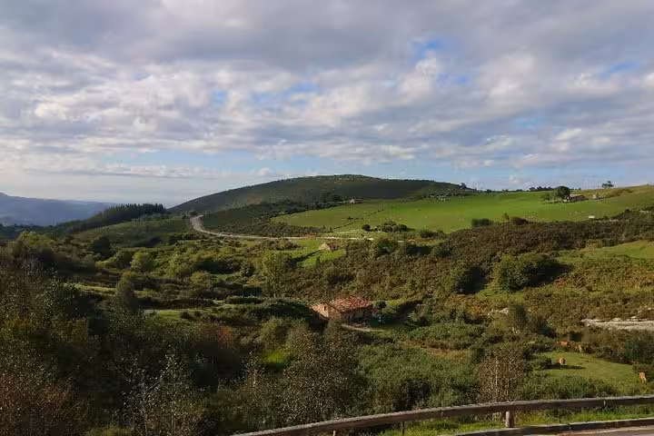 Rolling green countryside landscape with cloudy skies, typical of the El Soplao Cave tour region.