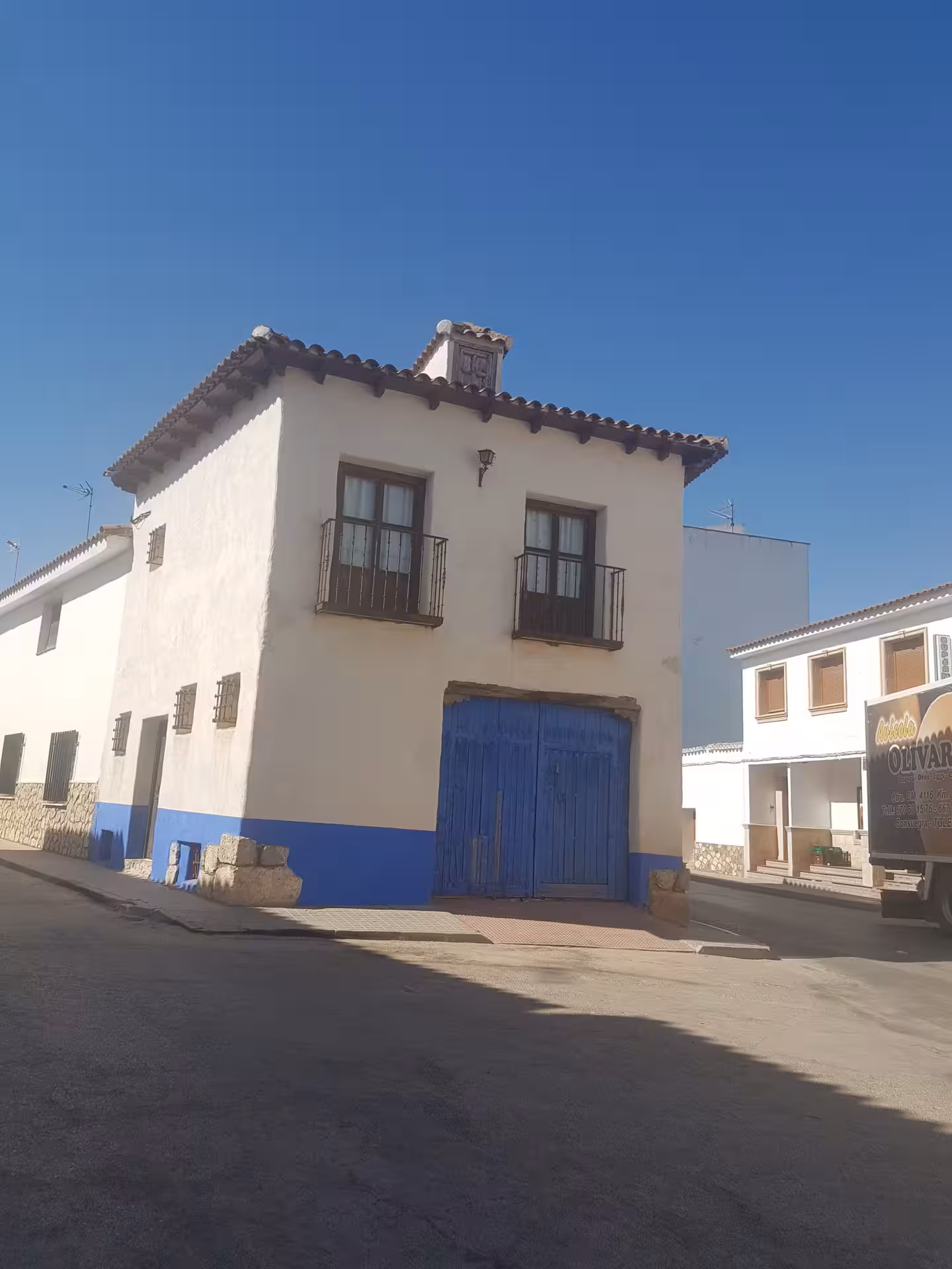 Whitewashed El Toboso house with blue door on a sunny street, authentic La Mancha village on the Don Quixote Tour