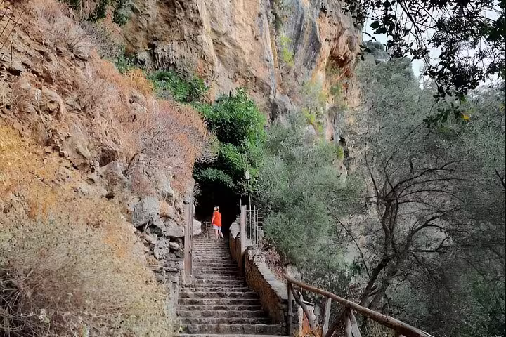 Visitor explores rustic stone steps leading to a cliffside cave on the Elafonisi Beach private tour.