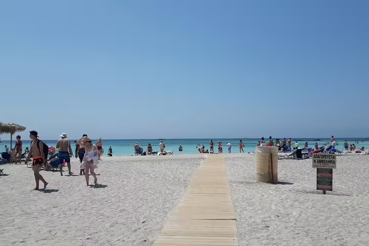 Visitors enjoy the sun at Elafonisi Beach, famous for its pink sand and turquoise waters, during a private tour from Chania.