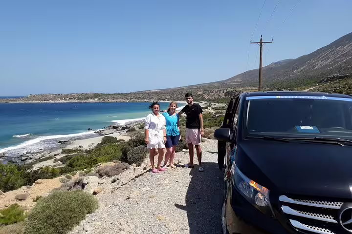 Group of tourists standing beside a tour vehicle overlooking a scenic coastal view near Elafonissi Beach.