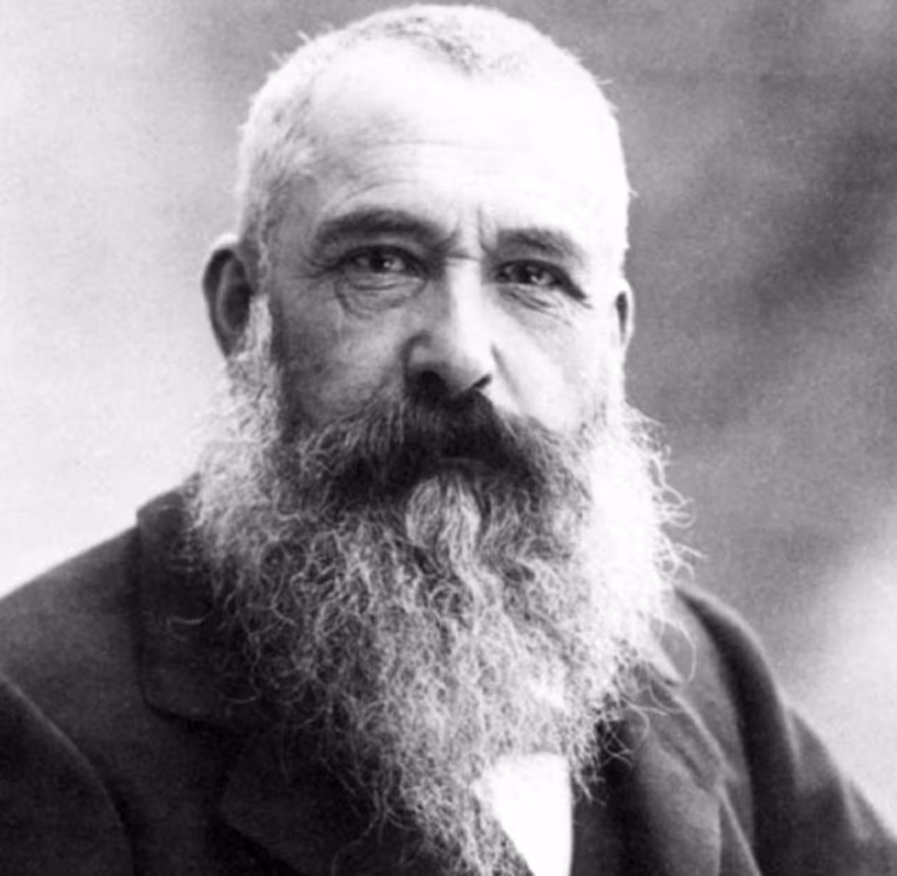 Black and white portrait of an elderly bearded man with white hair wearing a dark jacket