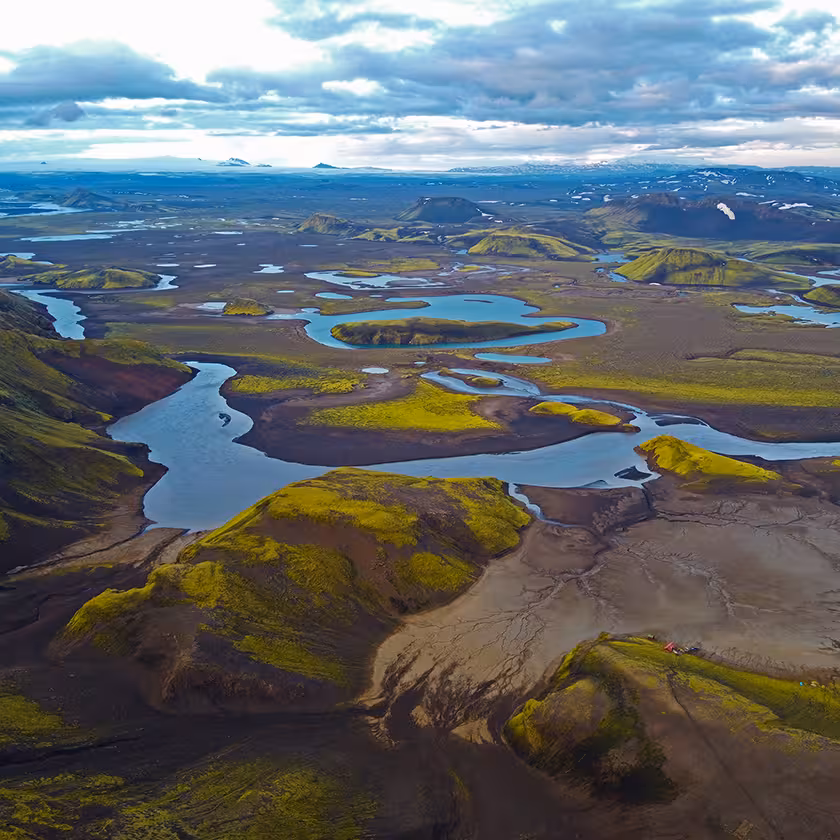 Aerial view of winding glacial rivers and green moss-covered lava fields in Iceland's highlands