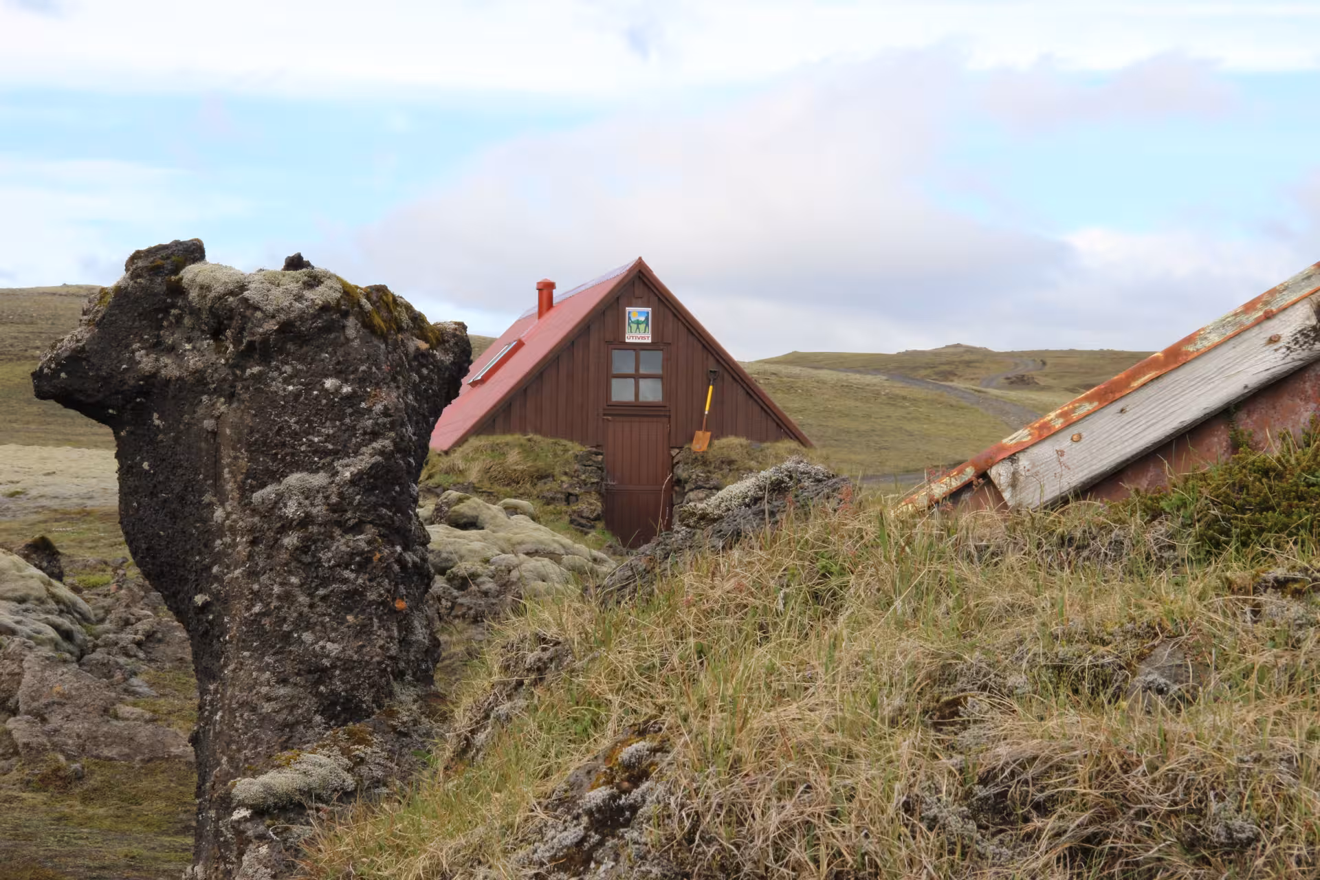 Red-roofed mountain hut nestled among mossy lava rocks in Iceland Highlands