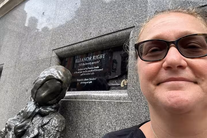 Woman taking selfie next to Eleanor Rigby statue and plaque in Liverpool on Beatles walking tour
