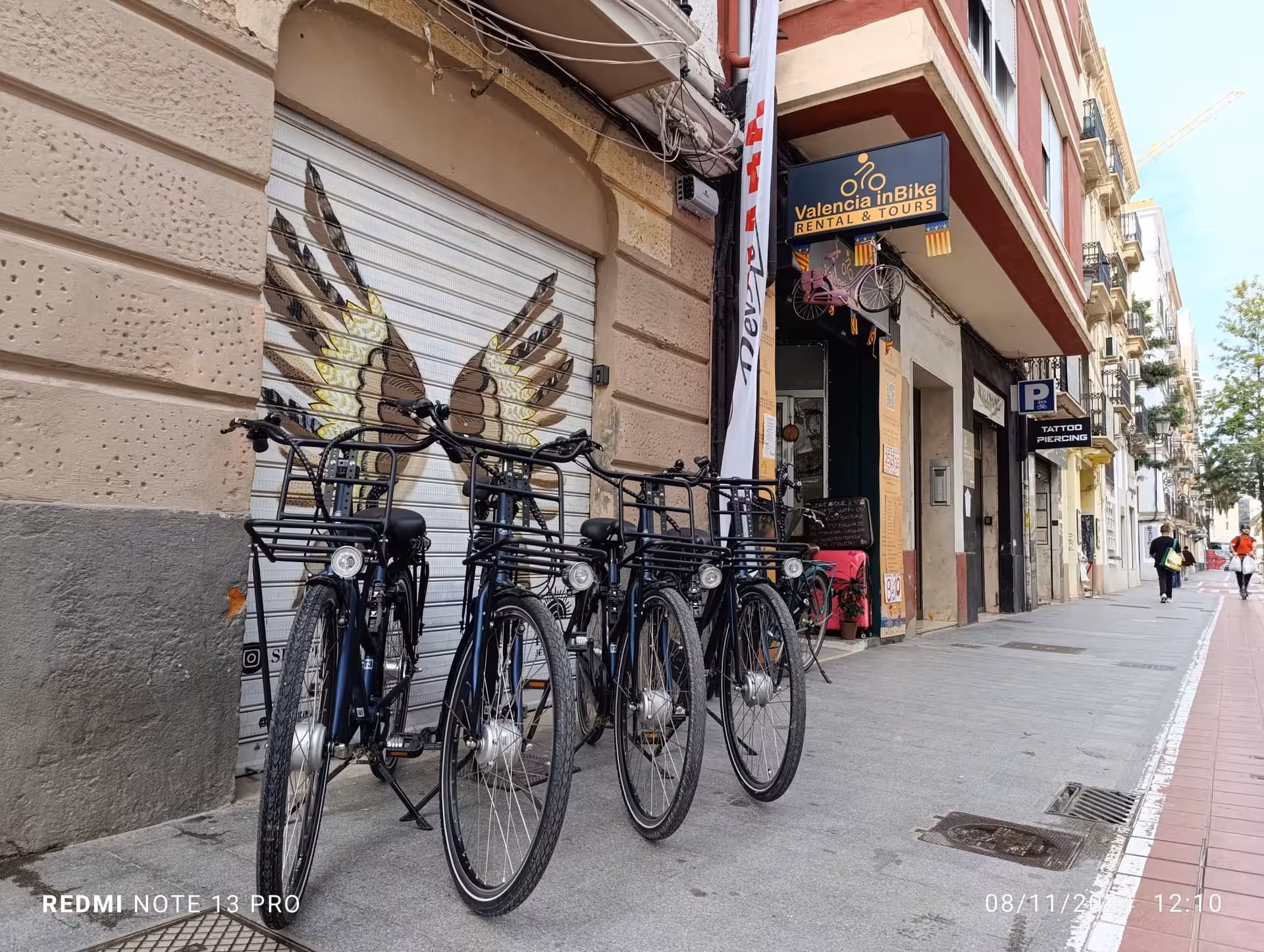Row of electric bikes at Valencia inBike rental and tours storefront on city street, perfect for e-bike hire