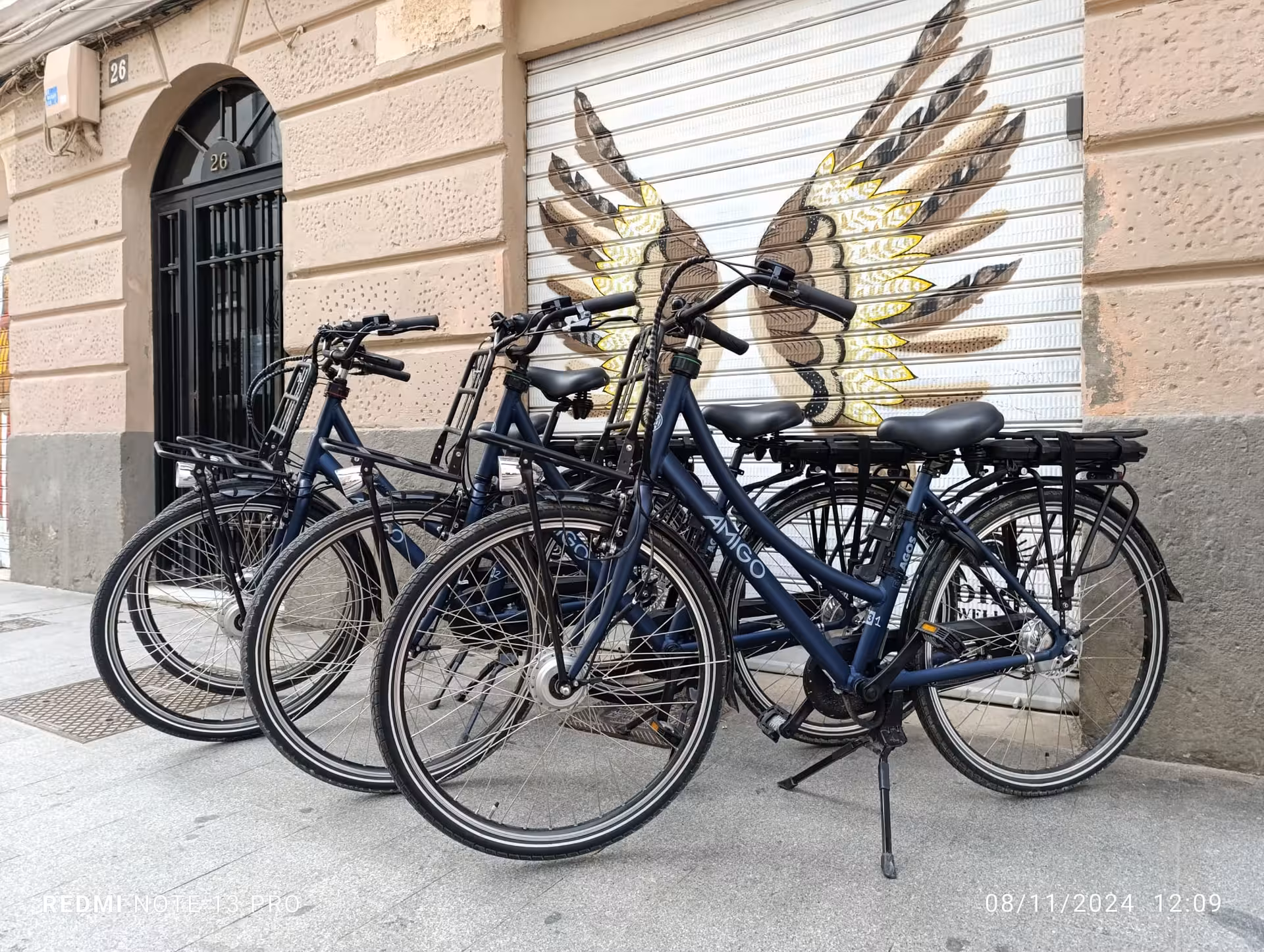 Fleet of electric rental bikes parked by street art mural, ideal for city e-bike rental and self-guided tours