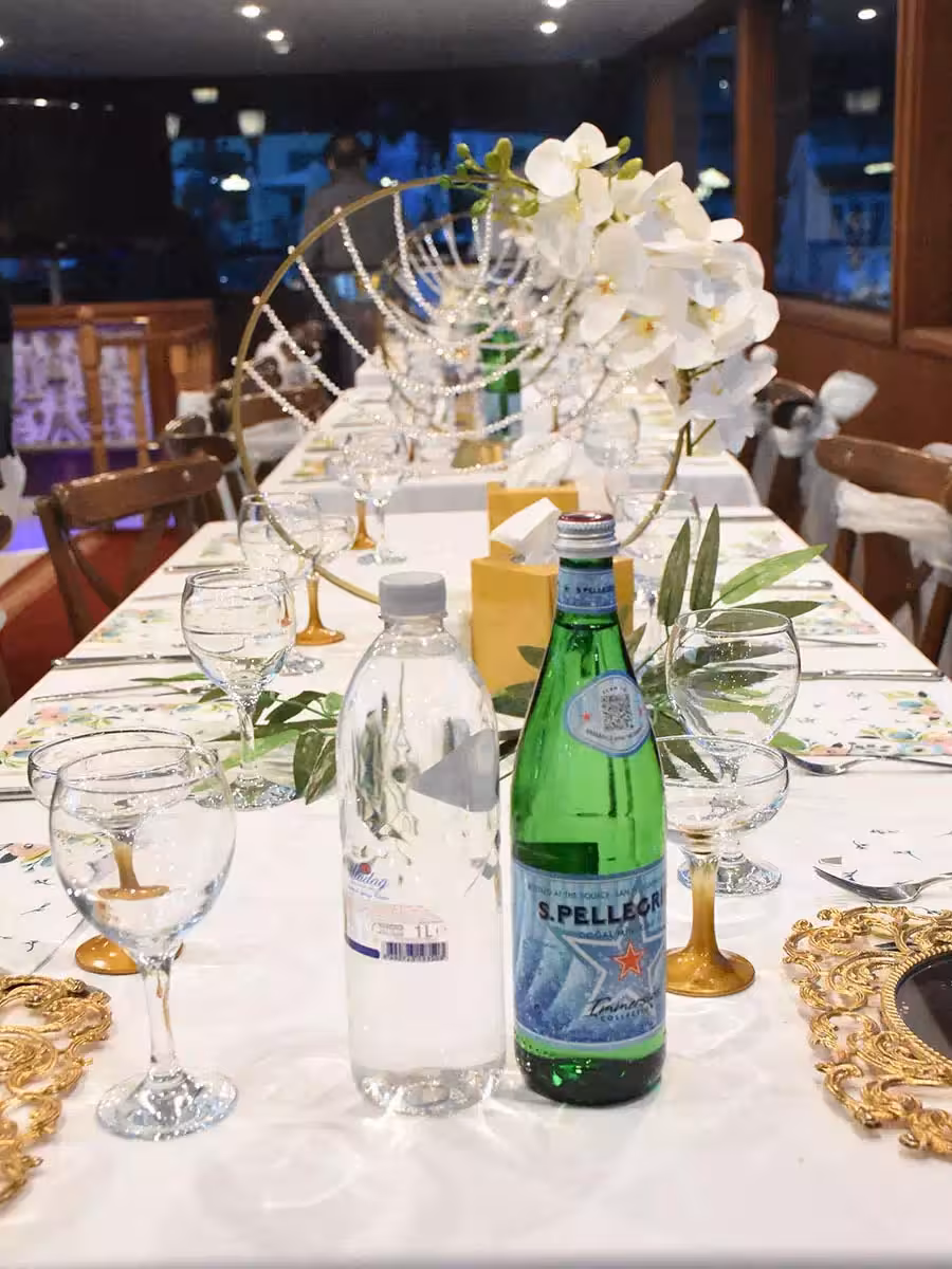 Elegant yacht birthday party table setup with orchid centerpiece, glassware, and sparkling water on board