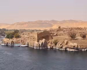 Elephantine Island rocky shores along the Nile River with desert hills and ancient ruins in Aswan, Egypt