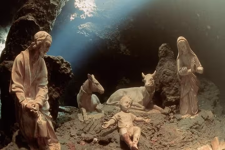 Intricate statues depicting a nativity scene illuminated by sunlight in the mystical Emerald Grotto, Amalfi Coast.