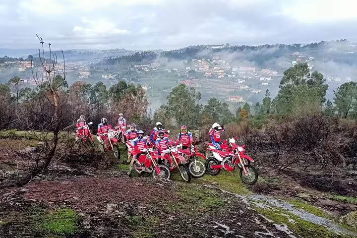Group of enduro bikers exploring scenic hills and valleys in Marco de Canaveses on a misty day.